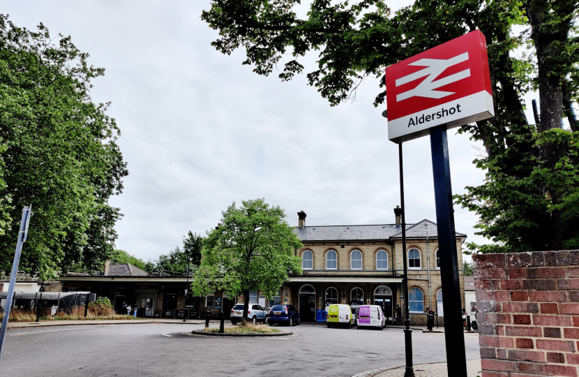 Picture of Aldershot Railway Station, with National Rail sign saying 'Aldershot' in the foreground.