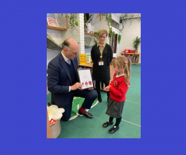 Leo Docherty MP at North Farnborough Infant School, presenting the winning design to Alice Childs, winner of the Schools Christmas Card Competition 2023