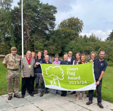 Wellesley Woodlands team and others holding the 'Green Flag', before raising it.